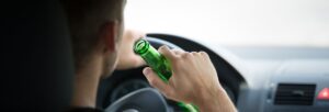Marino Lawyers Drunk driver behind steering wheel holding beer bottle
